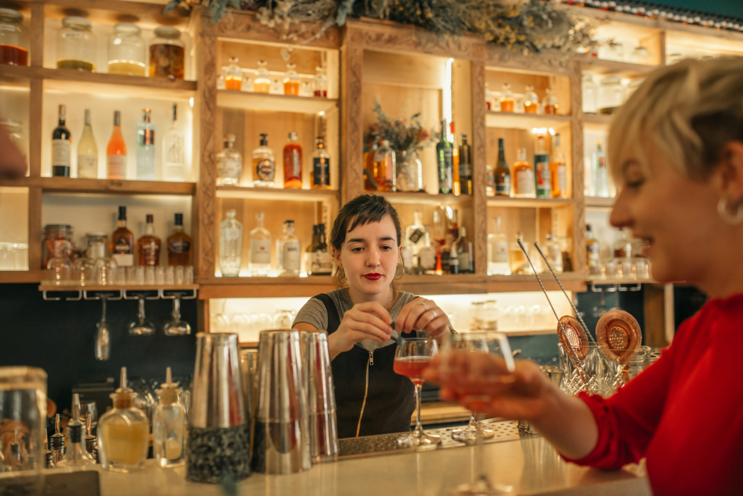 Photo d'une jeune femme qui vient d'ouvrir un bar en train de servir un cocktail
